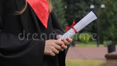 年轻女子，穿着学术服装，拿着文凭，享受<strong>毕业典礼</strong>